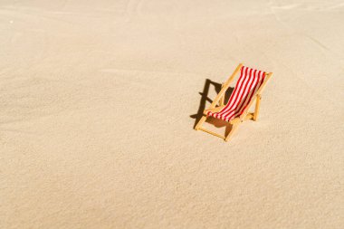 Bir güverte sandalyesi, güneş yatağı, dinlenme odası, bir bardak portakal suyu, parmak arası terlik, Lifebuoy, kumsaldaki palmiye ağacı. Yaz ve seyahat konsepti. Minimalizm