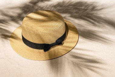 Palmiye dalları ve gölgeli palmiye ağaçları arasında kum üzerinde yaz hasarı şapkası. Seyahat, tatil, yaz tatili konsepti. Üst görünüm.