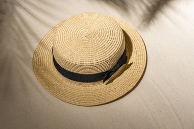 Palmiye dalları ve gölgeli palmiye ağaçları arasında kum üzerinde yaz hasarı şapkası. Seyahat, tatil, yaz tatili konsepti. Üst görünüm.