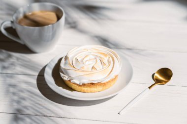Tahtaya konmuş limonlu küçük turta palmiye dallarının gölgelerindeki açık hava kafeteryasında masa. Bir fincan kahveyle Avrupai kahvaltı.