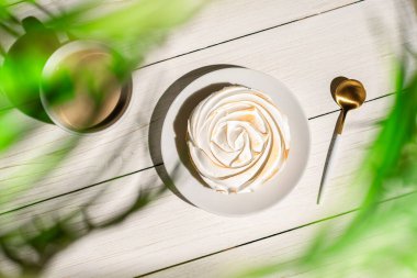 Tahtaya konmuş limonlu küçük turta palmiye dallarının gölgelerindeki açık hava kafeteryasında masa. Bir fincan kahveyle Avrupai kahvaltı.