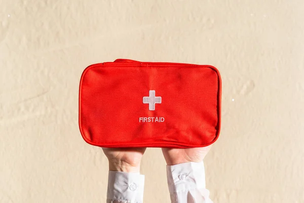 Hands of woman holing red emergency box on plain background