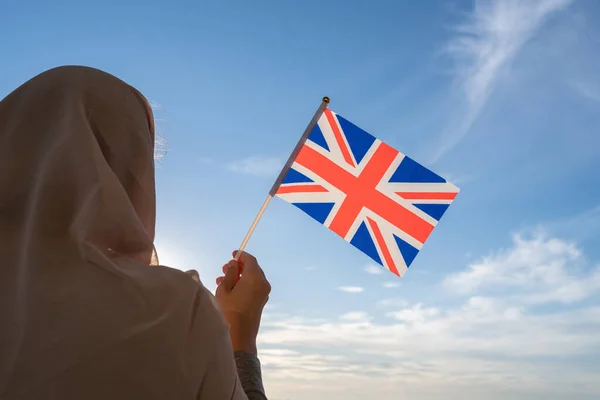 青い夕日の空に英国の旗と頭のスカーフでイスラム教徒の女性のシルエット 自由の概念 — ストック写真