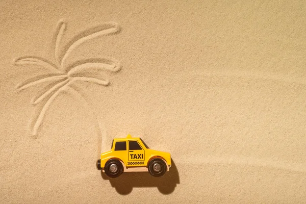 Toy taxi car, sun, palm tree on beach sand. Concept. Fast and cheap taxi booking service. Travel. Summer time. Creative