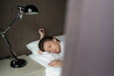 Yatakta Uyuyan Güzel Rahatlama Kadını. Sabahları rahat bir yatakta dinlenen güzel bir kadının portresi. İnsanlar uyur. Perde penceresinden bak.