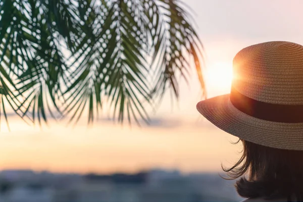 一个戴着草帽的漂亮姑娘倒映在海的背景上 在棕榈树的枝头上 日落海滩 夏天和自由的概念 — 图库照片