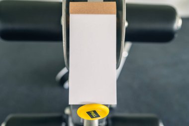 Spor aletlerinin ve koşu simülatörlerinin karşısındaki spor salonunda açık not defteri olan bir kadın eli. Uzayı kopyala, maketle