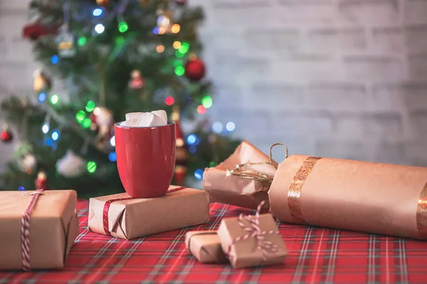 手工制作的圣诞礼物 红色杯子 热巧克力和融化的棉花糖 圣诞树 背景上有闪亮的花环和核桃 — 图库照片