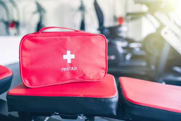 First aid kit red box in the fitness gym opposite the sport equipment and  jogging simulators. Healthy lifestyle, safety and help concept