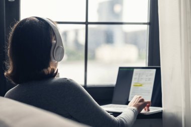 Yalnız bir kadının kulaklıkla müzik dinlemesi ve kafenin penceresinin yanında laptopla çalışması..