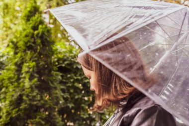 Sonbahar. Şeffaf bir şemsiye altında yalnız üzgün bir kadın. Parkta, bahçede yağmur damlaları geziyor. Yağmurlu bir manzara. Vintage Tone