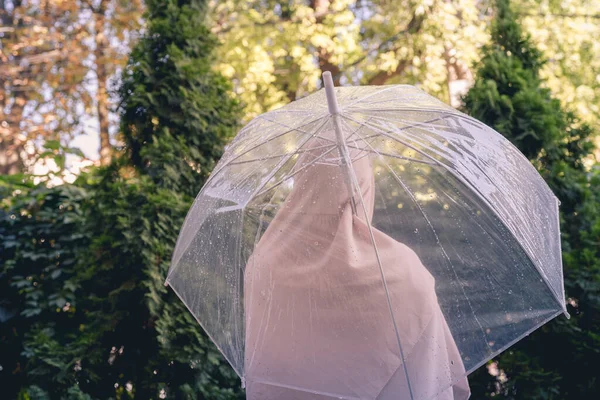 雨の透明な傘の下でスカーフの中に孤独なイスラム教徒の女性が公園 庭を歩いてドロップします 雨の日の風景 ヴィンテージトーン — ストック写真