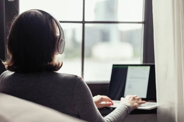 헤드폰을 음악을 카페의 창가에 노트북으로 일하는 외로운 여성의 뒷모습 — 스톡 사진