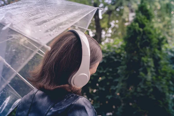 庭を歩いてヘッドフォンで孤独な悲しい女性 雨滴とぬれた透明な傘を通して表示します 雨の日の風景 ヴィンテージトーン — ストック写真