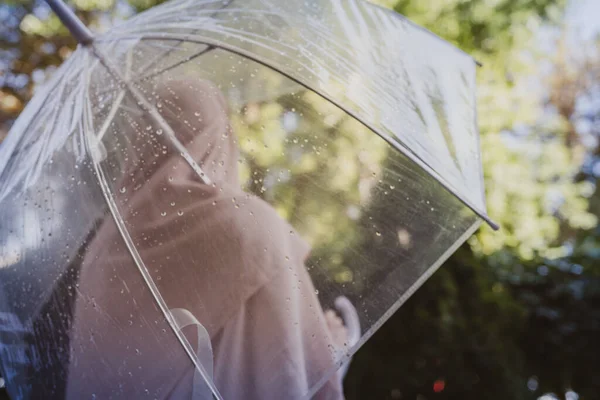 一个寂寞的穆斯林女人 头戴头巾 披着透明的雨伞 走在花园的公园里 雨天的风景 陈年旧酒 — 图库照片