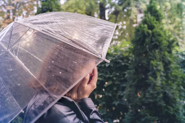 孤独な不幸な女性が手で彼女の顔を覆い 雨の中でぬれた透明な傘で公園 庭を歩いて泣く 二人の別れ — ストック写真