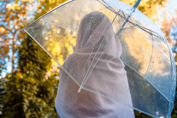 雨の透明な傘の下でスカーフの中に孤独なイスラム教徒の女性が公園 庭を歩いてドロップします 雨の日の風景 ヴィンテージトーン — ストック写真