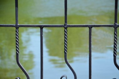 Suyun arka planına karşı metal koyu çit. Baraj gölünün yanında eskrim. Çit. Geçmişi. Kapatın. Yakın..