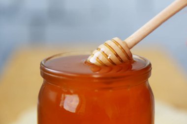 Bal için kurutma kaşığı bal dolu bir kavanozda. Tıp için tahta kaşık. Bal dolu cam bir kavanoz. Yakın çekim görüntüsü. Yemek pişirmek. Tatlı yemek. Doğal yiyecekler. Sağlıklı beslenme.