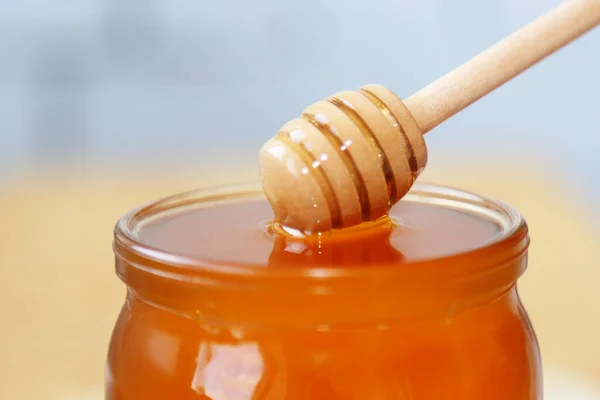 Tepeden tırnağa bal dolu küçük bir kavanoz. Bir sürü bal. Cam bir kapta bal var. Yaklaştın. Yandan manzara. Kavram: Doğal, sağlıklı ve tatlı yiyecekler. Çok lezzetli..