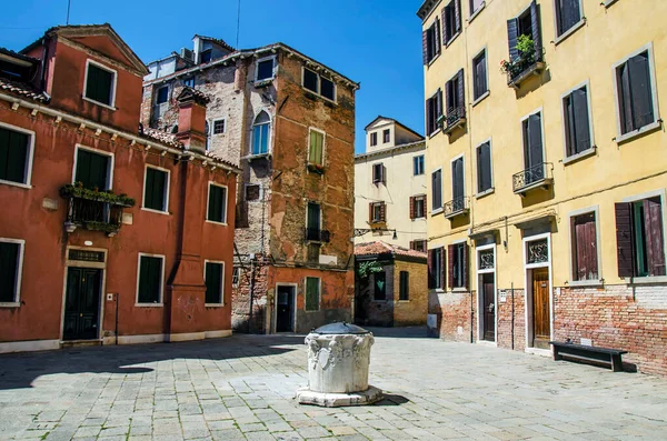 Yard with a well and colorful buildings in Venice, Italy. Italian square with colorful buildings in Venice