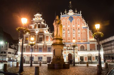Meşhur Kara Kafalar Evi 'nin gece görüşü ve Letonya' nın Riga şehrinde Noel süslemeleri yapılmış fenerler. Riga Belediye Meydanı 'nın ve Roland' ın Noel süslemeli heykelinin gece manzarası.