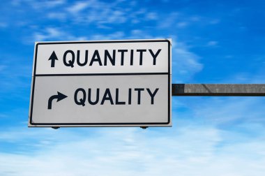 Niteliğe karşı nicelik. Metal direkli beyaz iki sokak işareti. Yönlü yol. Kavşak Yolu İşareti, İki Ok. Mavi gökyüzü arkaplanı.