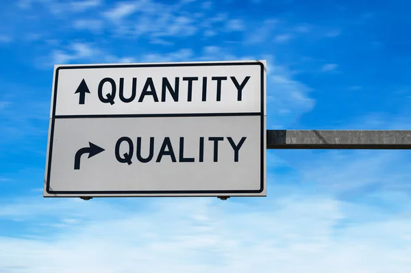 Quantity versus quality. White two street signs with arrow on metal pole. Directional road. Crossroads Road Sign, Two Arrow. Blue sky background.