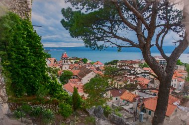 Dağlar, Cetina nehri ve denizle çevrili küçük bir kasaba olan Omis 'in suluboya etkisi, Hırvatistan' ın Makarska Riviera kenti. Çam ağacı manzarası, kırmızı çatıları ve mavisi olan eski şehir merkezi..