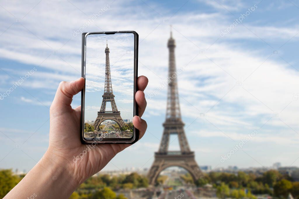 Tourist taking photo of Eiffel tower in Paris, France. Man holding phone and taking picture.