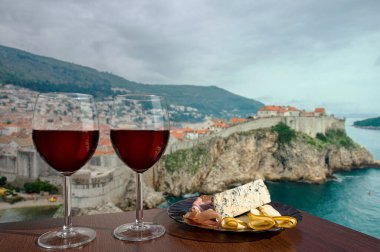 Hırvatistan 'ın Dubrovnik kentine karşı şarküteri çeşnili iki bardak şarap. Farklı atıştırmalıklarla bir bardak kırmızı şarap. Jambonlu, dilimlenmiş, mavi peynirli tabak. Romantik kutlama..