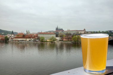 Çek Cumhuriyeti Prag 'daki nehir ve şehir merkezi manzaralı bir bardak light bira.