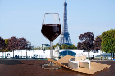 Eyfel Kulesi 'nin arka planında peynirli bir bardak şarap. Paris, Fransa 'daki Eyfel Kulesi' ne bakan kırmızı şarap kadehinin güneşli manzarası