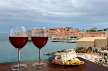 Dubrovnik şehir merkezine karşı şarküteri çeşnili iki bardak şarap. Tatil konsepti. Hırvatistan 'ın Dubrovnik kentinin tarihi merkezindeki sahil ve kent duvarı
