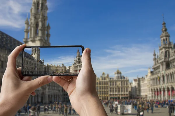 Tourist taking photo of Grand Place (Grote Markt) in Brussels, Belgium. Man holding phone and taking picture.