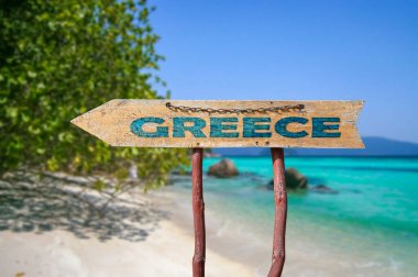 Wooden arrow road sign with word Greece against beach background. Travel to Greece concept.  clipart