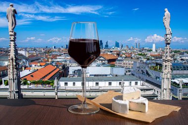 Bir bardak Brie peynirli kırmızı şarap Milano, İtalya 'nın manzarasına karşı