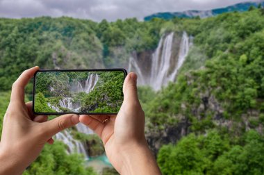 Hırvatistan 'daki Plitvice Gölleri Ulusal Parkı' nda büyük şelalenin fotoğrafını çeken turist