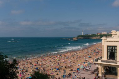 Arka planda deniz feneri olan Biarritz plajı.
