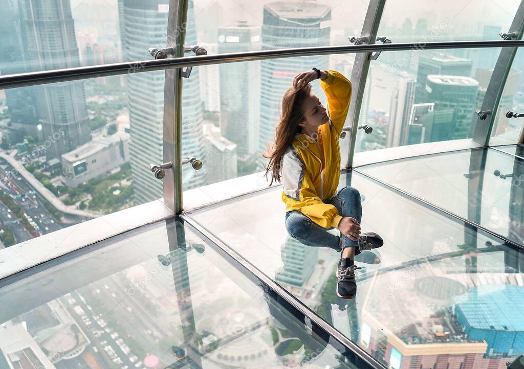 Beautiful girl sitting on top of a skyscraper in Shanghai. China 