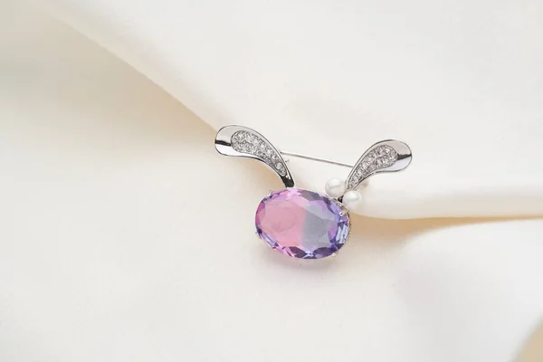 Серебряная брошь в форме зайца с фиолетовым радужным кристаллом — стоковое фото