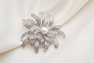 Küçük elmaslı gümüş broş ve beyaz arka planda izole edilmiş beyaz inci.. 