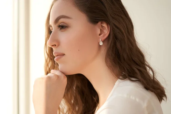 Fashionable portrait of a young beautiful girl with jewelry. Earrings with white crystals and diamonds. — Stock Photo, Image