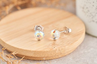 Yanardöner kristallerle yaklaş küpe. Tahta tabakta güzel küpeler. Kadın aksesuarları.