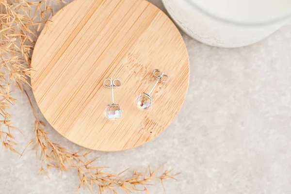 Близько шпильки сережки, з райдужними кристалами. Гарні сережки на дерев'яній тарілці. Жіночі аксесуари . — стокове фото
