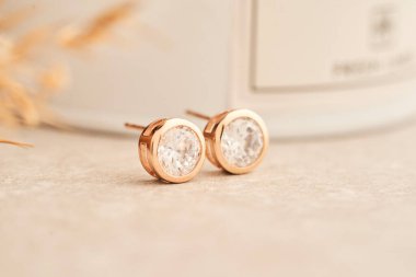 Beyaz kristaller ve elmaslarla altın küpeleri kapat. Beyaz arka planda güzel küpeler. 