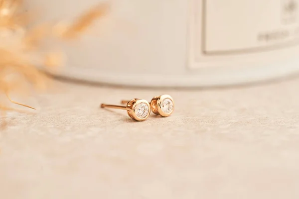 Close up golden stud earrings, with white crystals and diamonds. Beautiful earrings on white background.