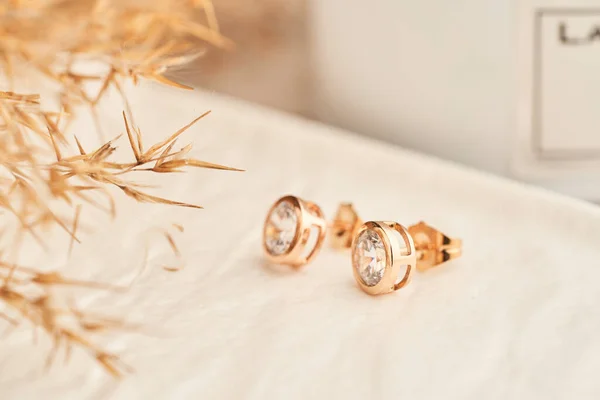 Крупним планом золоті сережки з білими кристалами та діамантами. Красиві сережки на білому тлі . — стокове фото
