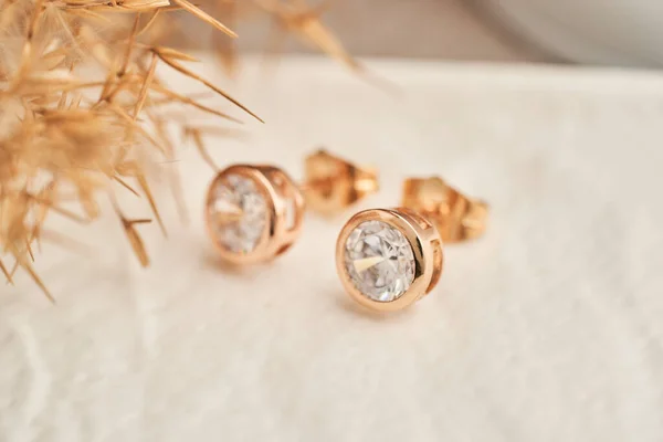 Feche os brincos dourados, com cristais brancos e diamantes. Brincos bonitos no fundo branco . — Fotografia de Stock