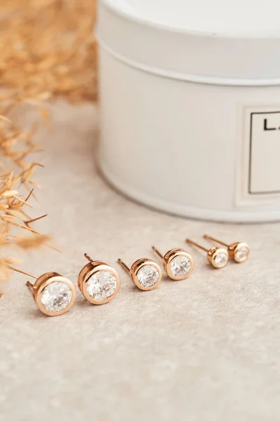 Close up golden stud earrings, with white crystals and diamonds. Beautiful earrings on white background.